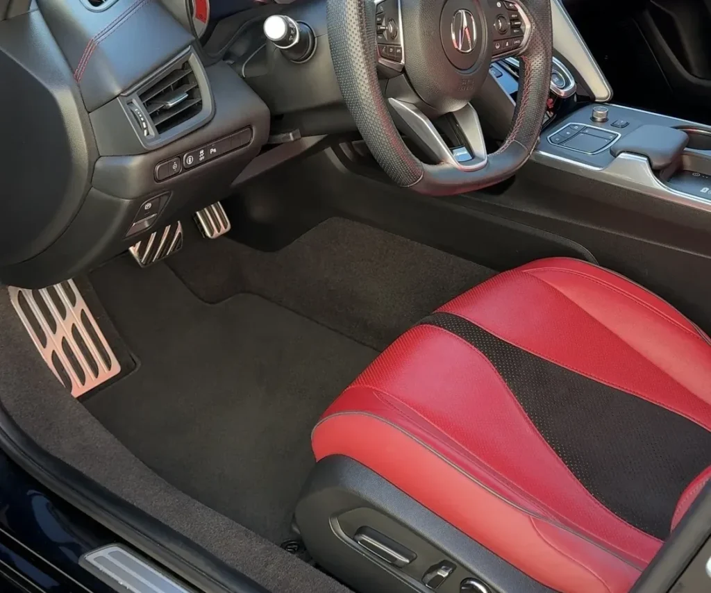 Finished interior of a red-leather Acura — dash, console and carpets detailed