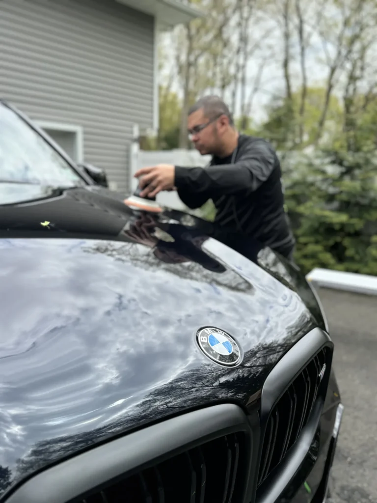 Machine polishing the hood of a black BMW